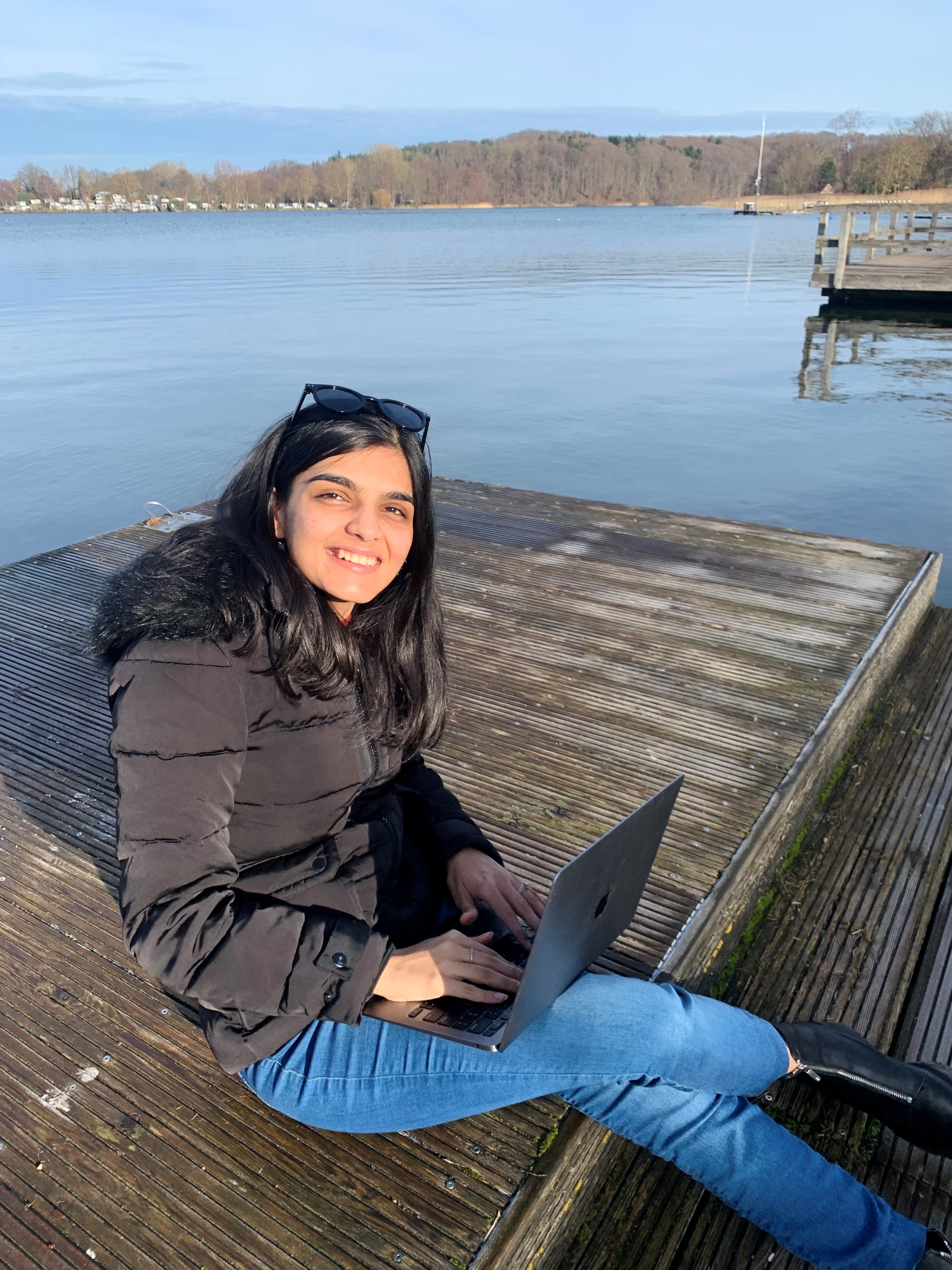 Pallavi sitting by the water with a laptop